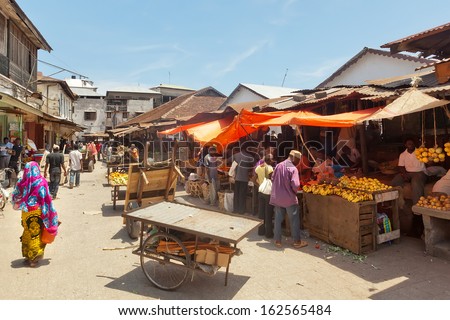 STONE TOWN, ZANZIBAR/TANZANIA - APRIL 4: City market under bright sun with sellers and buyers shown on 4 April 2012 in Zanzibar, Tanzania.