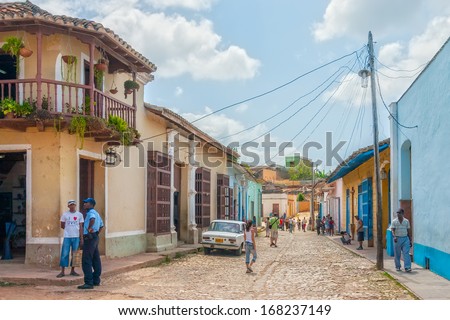TRINIDAD, CUBA - MAY 4: Car standing on the street with colored buildings near auto repair with mechanics  nearby shown on 4 May 2008 in Trinidad, Cuba. Trinidad has been one of UNESCOs World Heritage