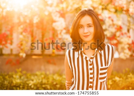 portrait of Happy Asia girl in the sunshine with flowers Background