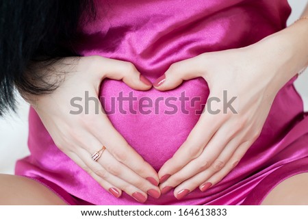 Pregnant girl hugging hands tummy. Hand of a woman hugging belly