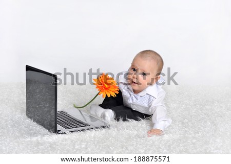 Cute baby with laptop on the white bed with flower