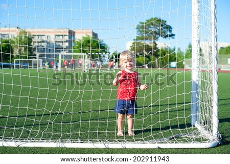 Little active football fan running on the green grass field with ball