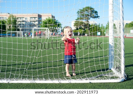Little active football fan running on the green grass field with ball