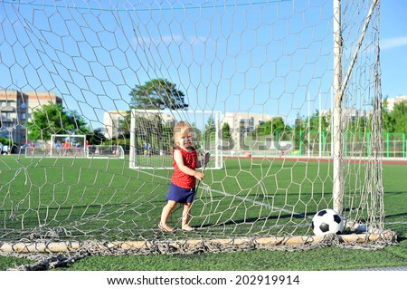 little girl baby blond / white hair resting on the grass / Outdoors. Little active football fan running on the green grass field with ball
