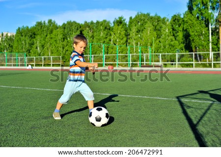 little boy playing football on football pitch
