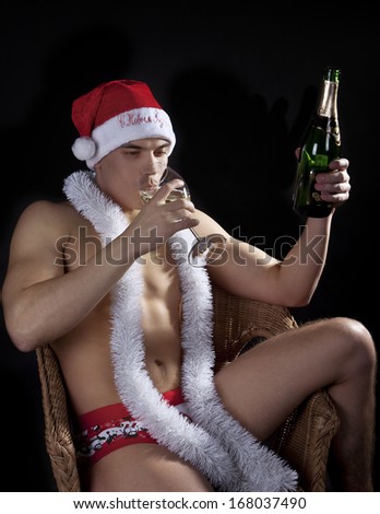 Guy Christmas shorts, cap and tinsel drinking champagne.
