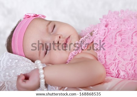 Cute baby is sleeping, lying down on the back of a pink suit