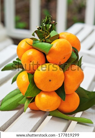 Fruit bouquet of tangerines lies on a white wooden chair on the balcony