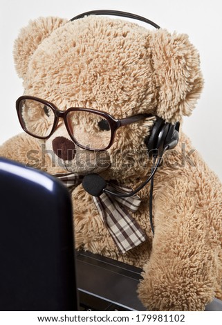 Funny bear in glasses and headphones at work behind the computer