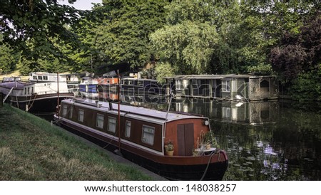 Narrow boat barge under the green trees in Cambridge, UK