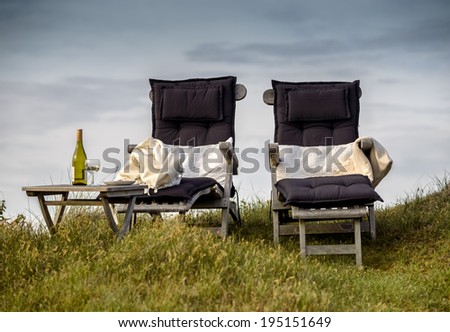 Two relaxation chairs and a glass of wine in the clear day light