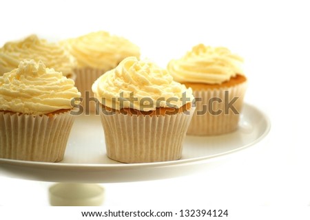 vanilla cup cakes on cake stand on white