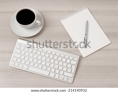 Computer desk with a cup of coffee, a notebook and pen