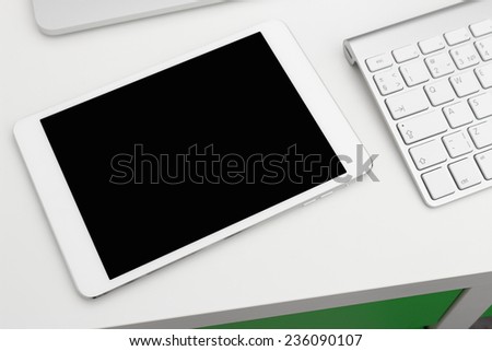 Tablet PC on a white table with a keyboard and a laptop
