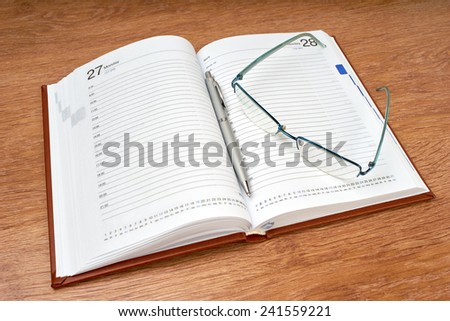 Daily planner with glasses and pen on the table