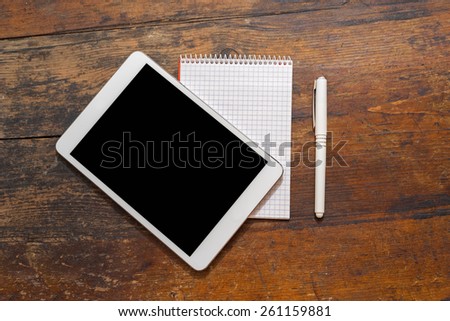 Digital tablet on wooden tablets with notepad and pen