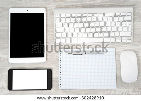 Office table with notebook, computer keyboard and mouse, tablet pc and smartphone
