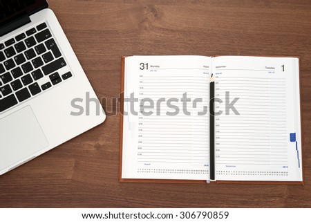 Diary and laptop on wooden table, top view