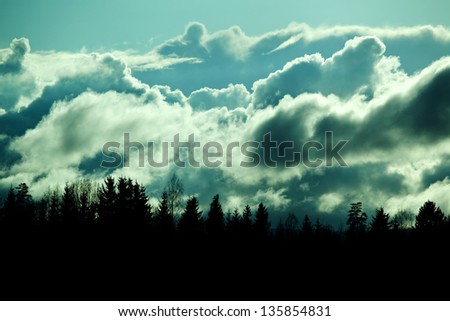 silhouette forest against beautiful, lighted clouds . Cloudscape in Oslo in dim light