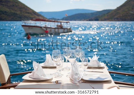 Elegant restaurant table waiting for customers by the sea; outdoor terrace in Perast, Montenegro
