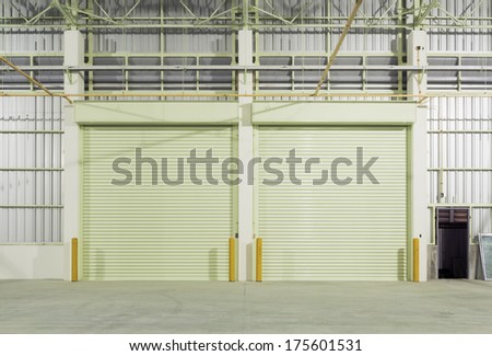 Interior Of Factory With Shutter Door, Night Time.