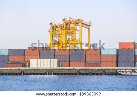 Container and crane at commercial port with blue sky background.
