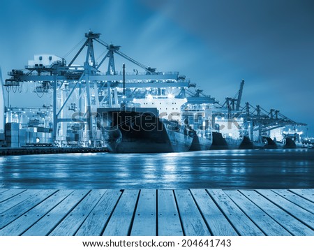 Cargo ship and crane at port reflect with river, twilight time (blue color tone).