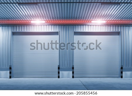 Exterior of factory with shutter door, night time.