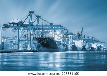 Cargo ship and crane at port reflect with water, twilight time (blue color tone).