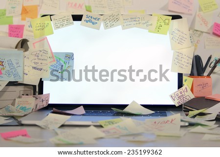 Office desk with laptop covered by post it papers