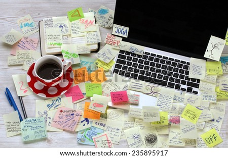 Office desk with laptop covered by post it papers