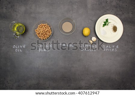 Hummus (Houmous) oriental recipe. Top view of ingredients on kitchen table. Olive oil, chick peas, sesame paste (tahini), lemon, garlic, salt, cumin.