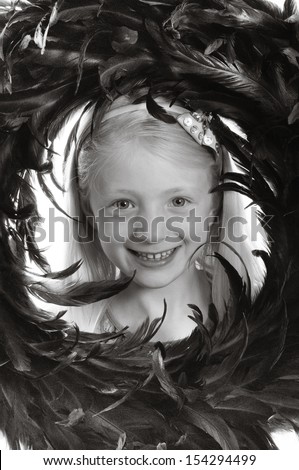 pretty blonde girl peeping through a feather wreath in monochrome