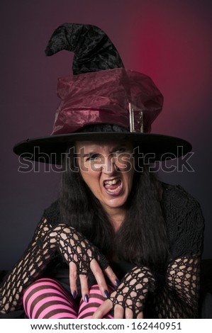 Halloween witch with stripey pink and black legs on red background