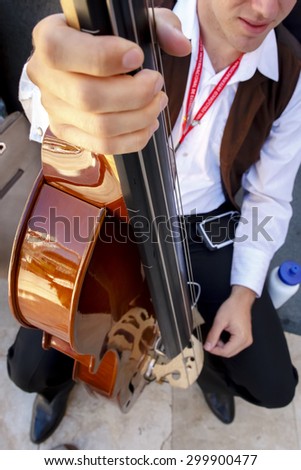 Musician playing the cello in the street. Musician recital giving abroad. Closeup of a cello.