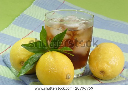 A glass full of Ice Tea with a lemon slice on green background