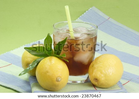 A glass full of Ice Tea with a lemon slice on green background