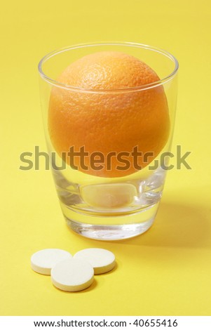 Effervescent tablets with glass and orange on yellow background