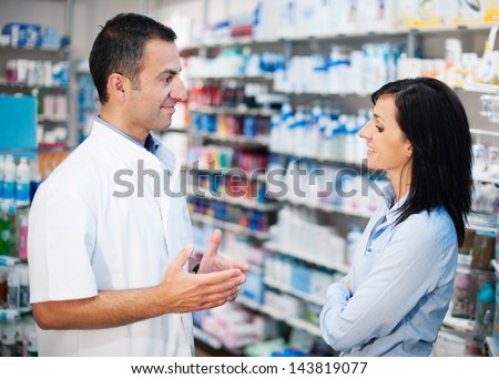 A great professional. The pharmacist resolves all doubts of his client. Photos taken on a real pharmacy. He wears a white coat as uniform