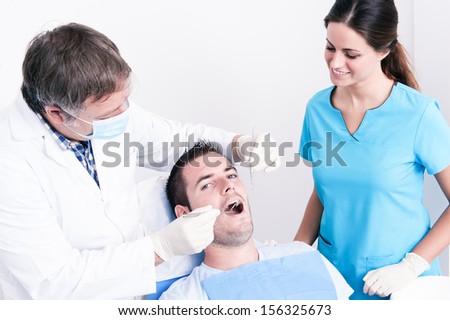 Dental surgery. There is a dentist, his assistant and the patient