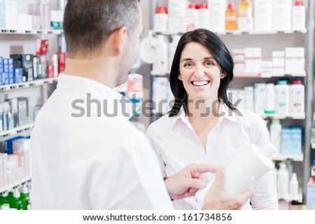 Smiling customer hand handsome pharmacist. The are in a real pharmacy