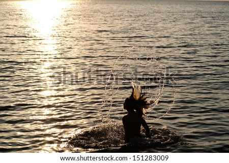 Young girl splashing water with her hair in the sea