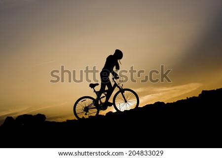 Silhouette of a young girl on mountain bike at sunset