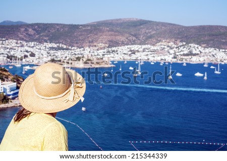 Hat woman is looking to the Bodrum Castle and  marina of Bodrum ,Turkey