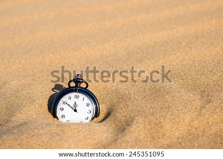 Pocket watch buried in sand