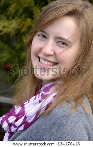 Portrait of pretty young woman outside in early Spring smiling with hair blowing in breeze