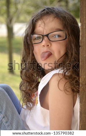 Outdoor portrait of a young girl sticking her tongue out