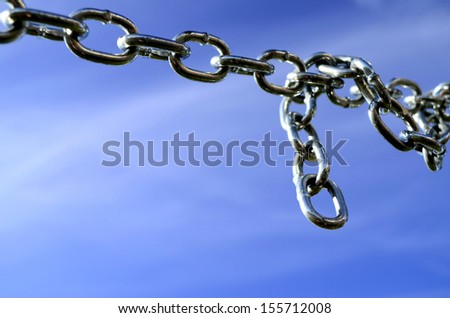 Detail of silver chain links against blue sky background at low angle