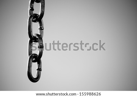 Monochrome image of the end of a metal chain showing four links on gray background