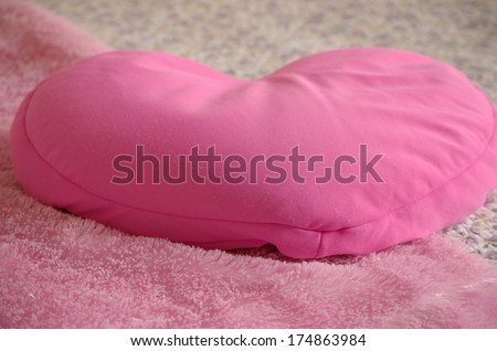 Soft pink heart pillow on fuzzy pink blanket and floral print quilt